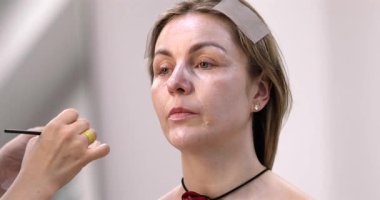 Profesyonel makyöz güzellik salonundaki güzel kadın modeline makyaj yapıyor..           