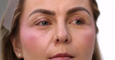 Makyöz, güzellik salonunda genç bir kadının profesyonel makyajını yapıyor.                