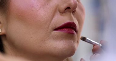 Makyöz, güzellik salonunda genç bir kadının profesyonel makyajını yapıyor.                