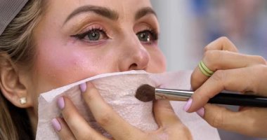 Güzellik salonundaki güzel kız modelin dudaklarına makyaj yapan profesyonel makyözün yakın plan görüntüsü.                 