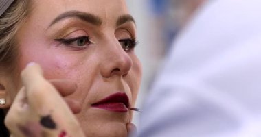 Güzellik salonundaki güzel kız modelin dudaklarına makyaj yapan profesyonel makyözün yakın plan görüntüsü.                 