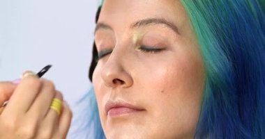 Parlak makyaj yapma süreci. Makyöz yüzüne makyaj yapan bir makyöz. Güzellik salonundaki genç yeşil saçlı kadının portresi..                        