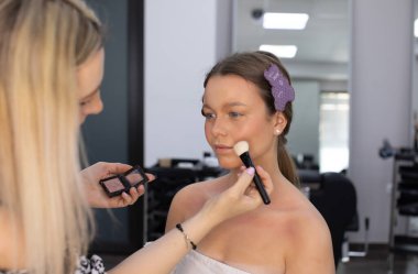 Profesyonel bir sanatçının güzellik salonuna makyajını yapan genç bir kadın.      