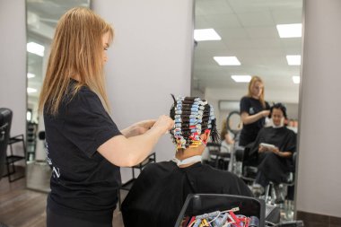 Müşteri ile çalışan profesyonel kuaför, yakın plan. Kuaför perma çubukları. Saç bigudileri.                           