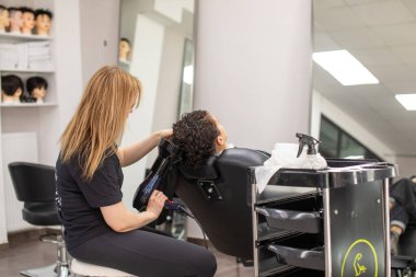 Güzellik salonunda saç kurutma makinesi olan kadın, yakın plan. Kadın müşterinin saçını kurutan kuaför.      