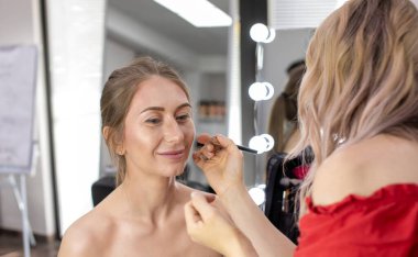 Profesyonel makyöz güzellik salonundaki güzel bayan modellere makyaj yapıyor..                       