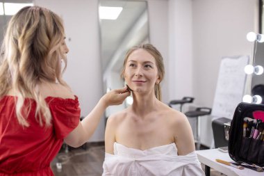 Profesyonel makyöz güzellik salonundaki güzel bayan modellere makyaj yapıyor..                       