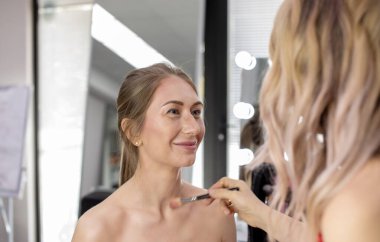 Profesyonel makyöz güzellik salonundaki güzel bayan modellere makyaj yapıyor..                       