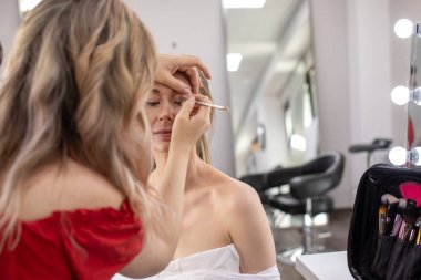 Profesyonel makyöz güzellik salonundaki güzel bayan modellere makyaj yapıyor..                       