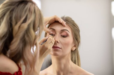 Profesyonel makyöz güzellik salonundaki güzel bayan modellere makyaj yapıyor..                       