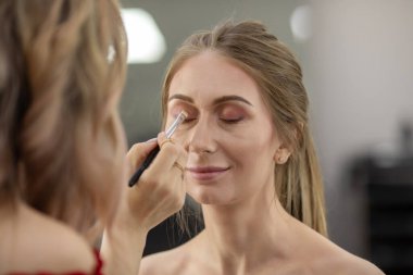 Profesyonel makyöz güzellik salonundaki güzel bayan modellere makyaj yapıyor..                       