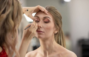 Profesyonel makyöz güzellik salonundaki güzel bayan modellere makyaj yapıyor..                       