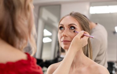 Profesyonel makyöz güzellik salonundaki güzel bayan modellere makyaj yapıyor..                       