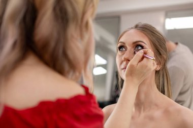 Profesyonel makyöz güzellik salonundaki güzel bayan modellere makyaj yapıyor..                       