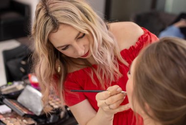 Profesyonel makyöz güzellik salonundaki güzel bayan modellere makyaj yapıyor..                       