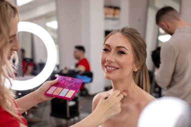 Profesyonel makyöz güzellik salonundaki güzel bayan modellere makyaj yapıyor..                       