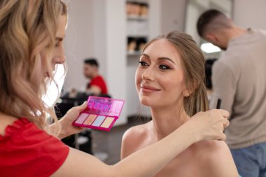 Profesyonel makyöz güzellik salonundaki güzel bayan modellere makyaj yapıyor..                       