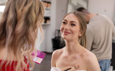 Profesyonel makyöz güzellik salonundaki güzel bayan modellere makyaj yapıyor..                       