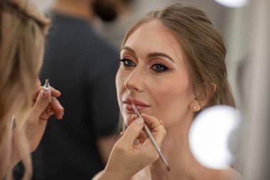 Profesyonel makyöz güzellik salonundaki güzel bayan modellere makyaj yapıyor..                       