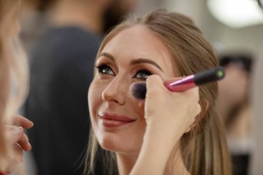 Profesyonel makyöz güzellik salonundaki güzel bayan modellere makyaj yapıyor..                       