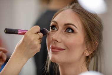 Profesyonel makyöz güzellik salonundaki güzel bayan modellere makyaj yapıyor..                       