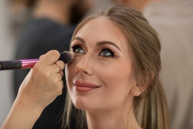 Profesyonel makyöz güzellik salonundaki güzel bayan modellere makyaj yapıyor..                       