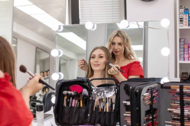 Profesyonel makyöz güzellik salonundaki güzel bayan modellere makyaj yapıyor..                       