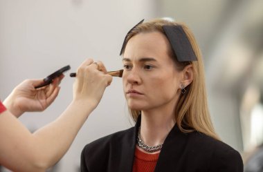 Makyaj sanatçısı genç ve güzel bir kadınla profesyonel makyaj yapıyor..        