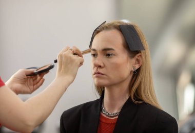 Makyaj sanatçısı genç ve güzel bir kadınla profesyonel makyaj yapıyor..        