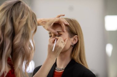 Makyaj sanatçısı genç ve güzel bir kadınla profesyonel makyaj yapıyor..        