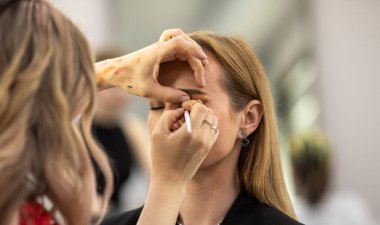 Makyaj sanatçısı genç ve güzel bir kadınla profesyonel makyaj yapıyor..        