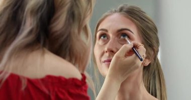 Profesyonel makyöz güzellik salonundaki güzel bayan modellere makyaj yapıyor..                       