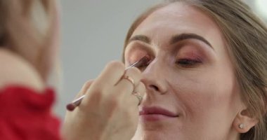 Profesyonel makyöz güzellik salonundaki güzel bayan modellere makyaj yapıyor..                       