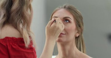 Profesyonel makyöz güzellik salonundaki güzel bayan modellere makyaj yapıyor..                       