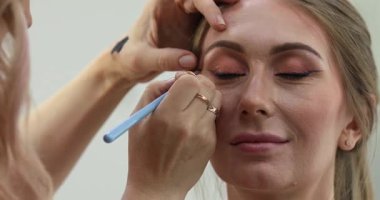 Profesyonel makyöz güzellik salonundaki güzel bayan modellere makyaj yapıyor..                       