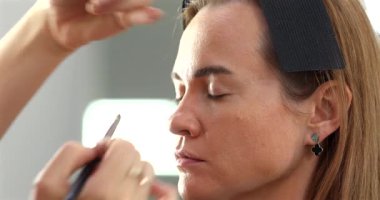 Profesyonel makyöz güzellik salonundaki güzel bayan modellere makyaj yapıyor..               