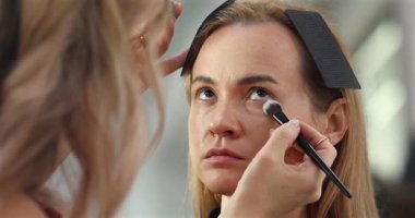 Profesyonel makyöz güzellik salonundaki güzel bayan modellere makyaj yapıyor..               