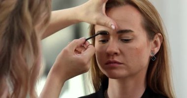 Profesyonel makyöz güzellik salonundaki güzel bayan modellere makyaj yapıyor..               