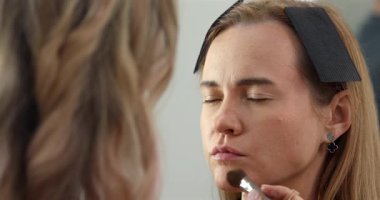 Profesyonel makyöz güzellik salonundaki güzel bayan modellere makyaj yapıyor..               