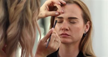 Profesyonel makyöz güzellik salonundaki güzel bayan modellere makyaj yapıyor..               