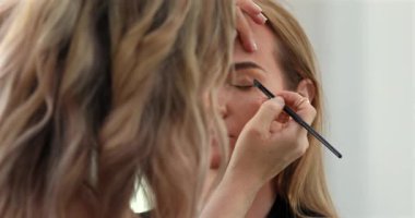 Profesyonel makyöz güzellik salonundaki güzel bayan modellere makyaj yapıyor..               