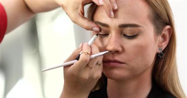 Makyaj sanatçısı genç ve güzel bir kadınla profesyonel makyaj yapıyor..        