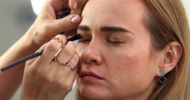 Makyaj sanatçısı genç ve güzel bir kadınla profesyonel makyaj yapıyor..        