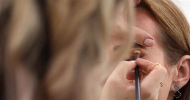 Makyaj sanatçısı genç ve güzel bir kadınla profesyonel makyaj yapıyor..        