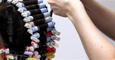 Müşteri ile çalışan profesyonel kuaför, yakın plan. Kuaför perma çubukları. Saç bigudileri.              