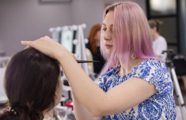 Profesyonel makyöz güzellik salonundaki güzel bayan modellere makyaj yapıyor..                   