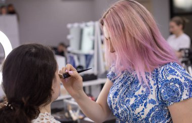 Profesyonel makyöz güzellik salonundaki güzel bayan modellere makyaj yapıyor..                   