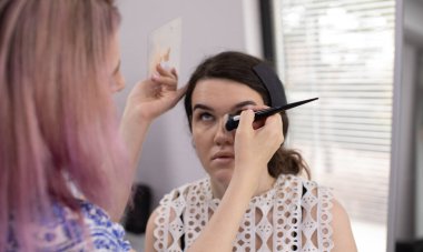 Profesyonel makyöz güzellik salonundaki güzel bayan modellere makyaj yapıyor..                   