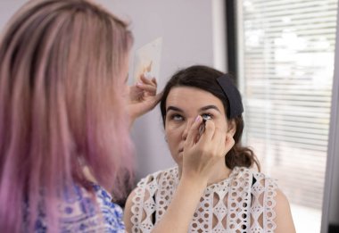 Profesyonel makyöz güzellik salonundaki güzel bayan modellere makyaj yapıyor..                   