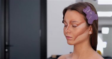 Profesyonel makyöz güzellik salonunda güzel bir genç kadın için makyaj yapıyor.                                   